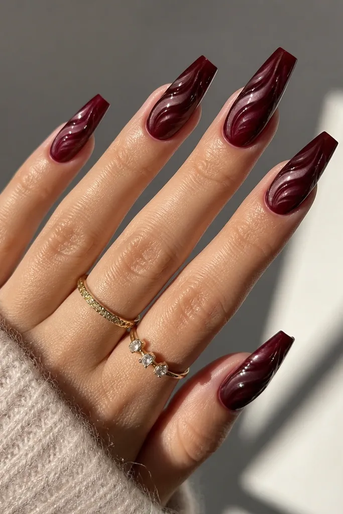 Coffin nails with a smooth dark cherry red gradient from tip to base, plus a glossy clear swirl pattern over the top that catches light.