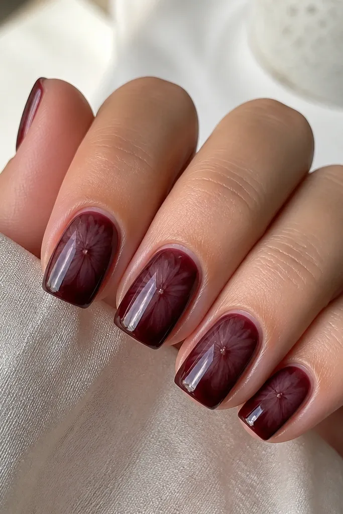 Square nails in deep dark cherry red with a smoky, translucent gray-violet burst centered on each nail, the edges feathered like stained glass, finished with a glossy top coat and a thin, clear gel outline around the burst.