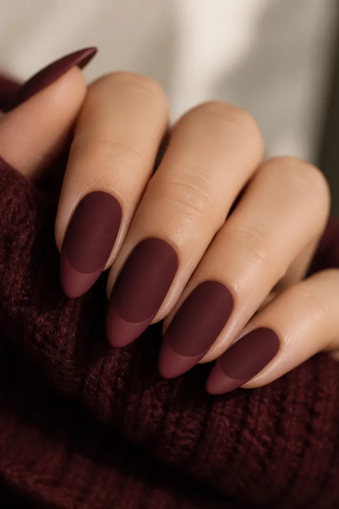 Almond nails with a dark cherry base that looks soft and velvety. The French tip is slightly lighter cherry and both sections are matte, with no shine except a faint velour texture.