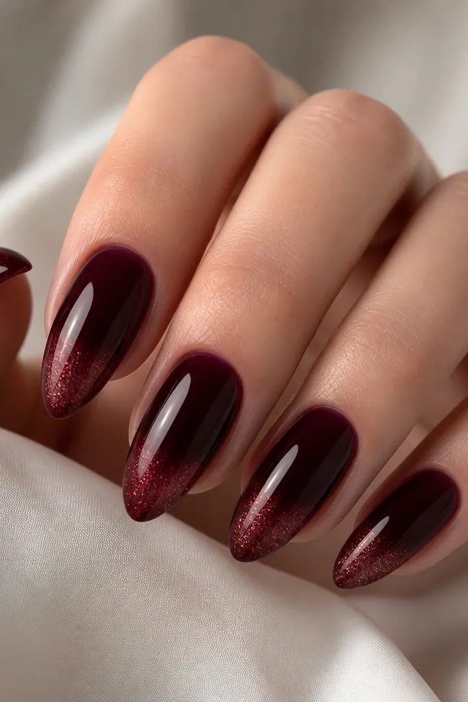 Almond nails with dark cherry base and a French tip that fades from solid burgundy micro-glitter at the edge to clear near the smile line. The rest of the nail is glossy and smooth.