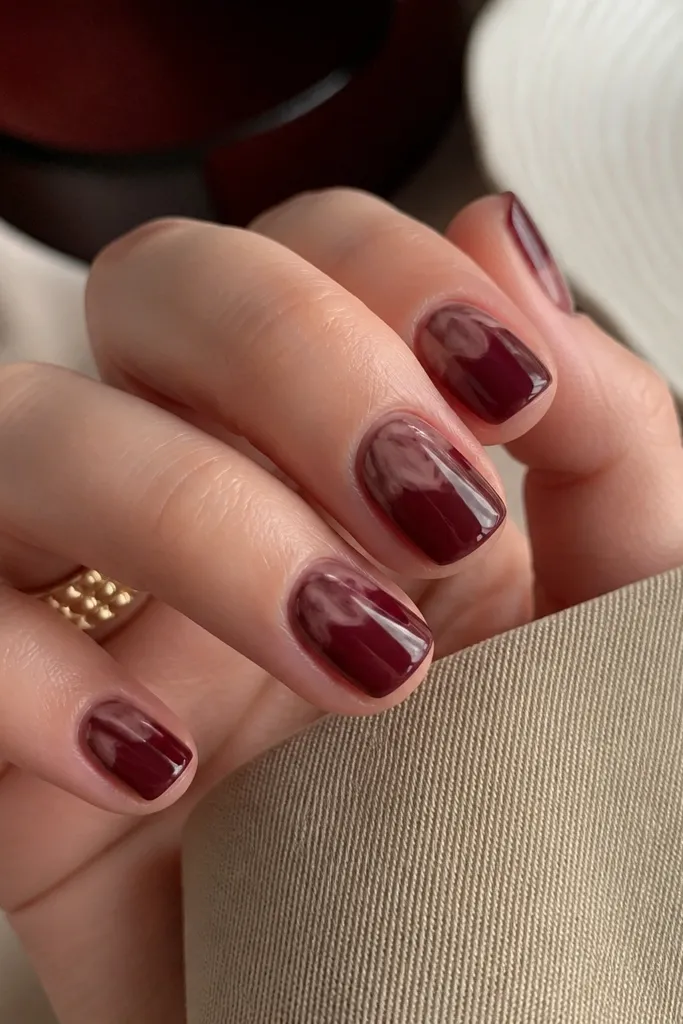 Short nails with a dark cherry base; marbled swirls in lighter cherry and taupe appear only on the top third near the tips.