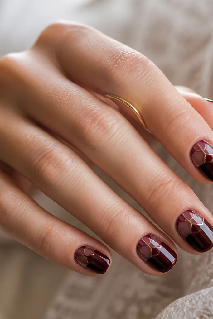 Short nails with dark cherry base; the top half has stained glass panels in translucent burgundy and clear gloss, separated by thin lines; glossy.
