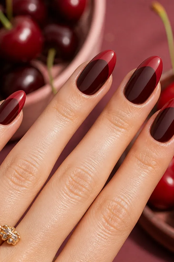Almond nails with a darker cherry base and a slightly lighter cherry crème tip. The color change is a smooth, curved gradient band near the free edge.