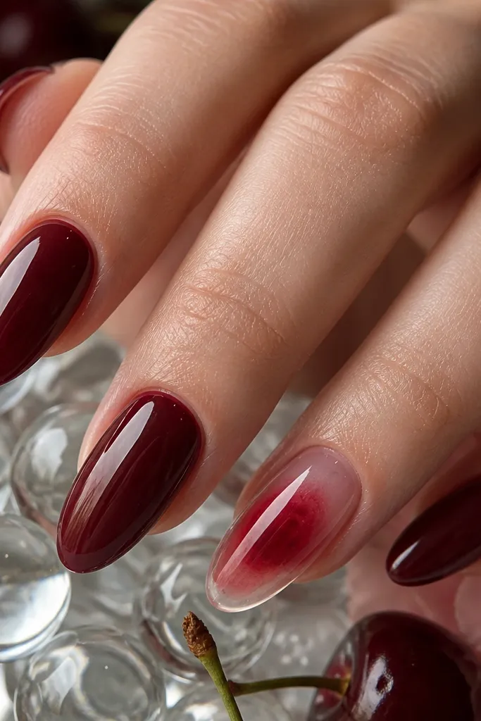 Almond nails with dark cherry base and one accent nail featuring a clear jelly panel. The jelly catches light and sits over the cherry, creating a layered, glassy look.