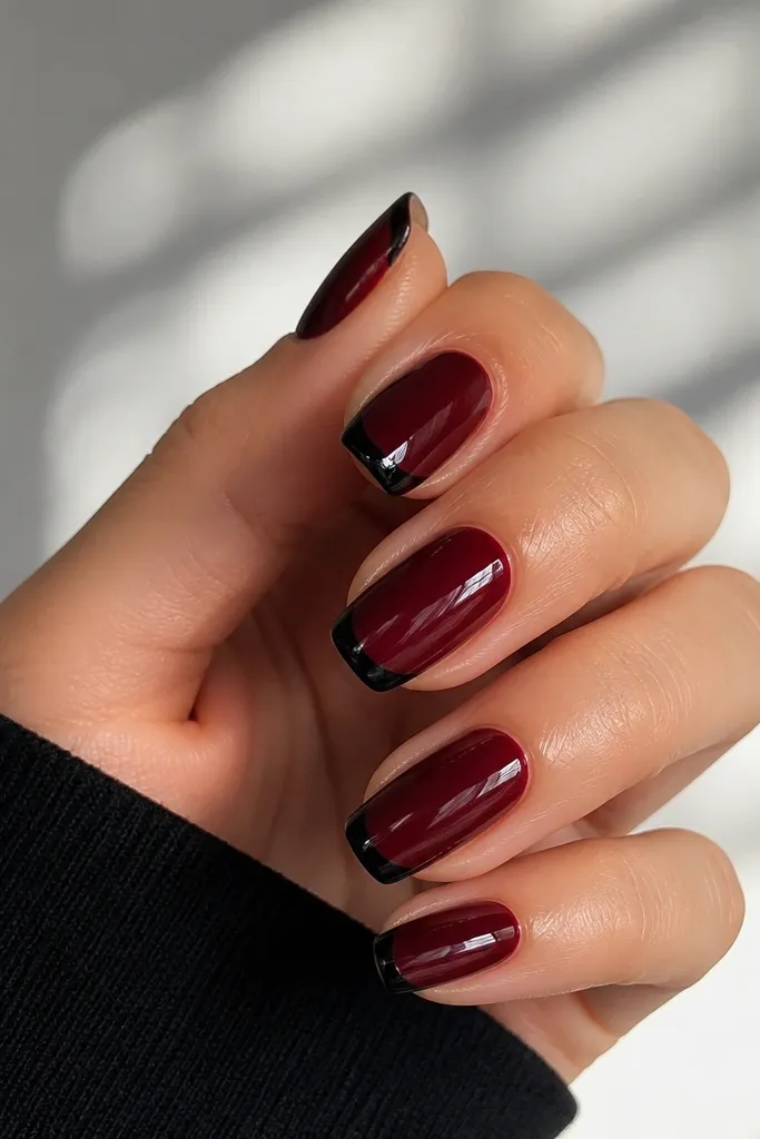 Dark cherry red nails with a French tip outlined in black. The inside of the tip is still dark cherry, but the outline is a sharp black line tracing the curve at the edge. Glossy finish.