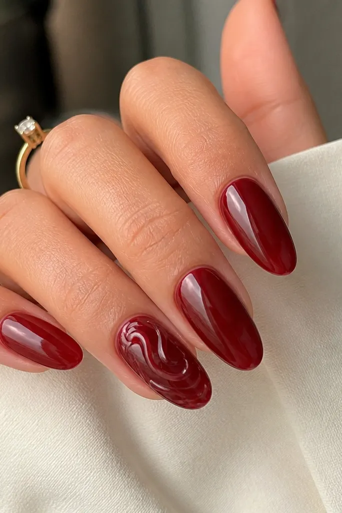 Translucent-looking dark cherry red nails with a clear gel swirl design on one accent nail. The swirl is glossy and looks like it's sitting on top, with smooth curves. Other nails are solid jelly cherry. Glossy finish.