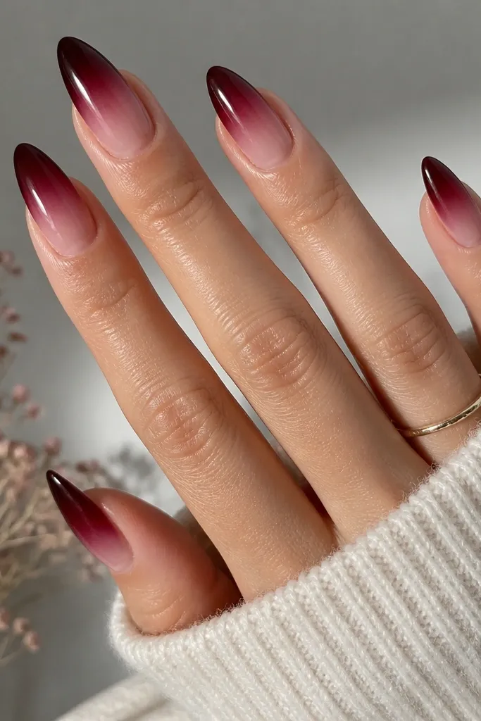 Almond nails with a smooth ombré: dark cherry is strongest at the tips and fades into a clear pink near the cuticle. The transition is blended with no harsh line; glossy finish.