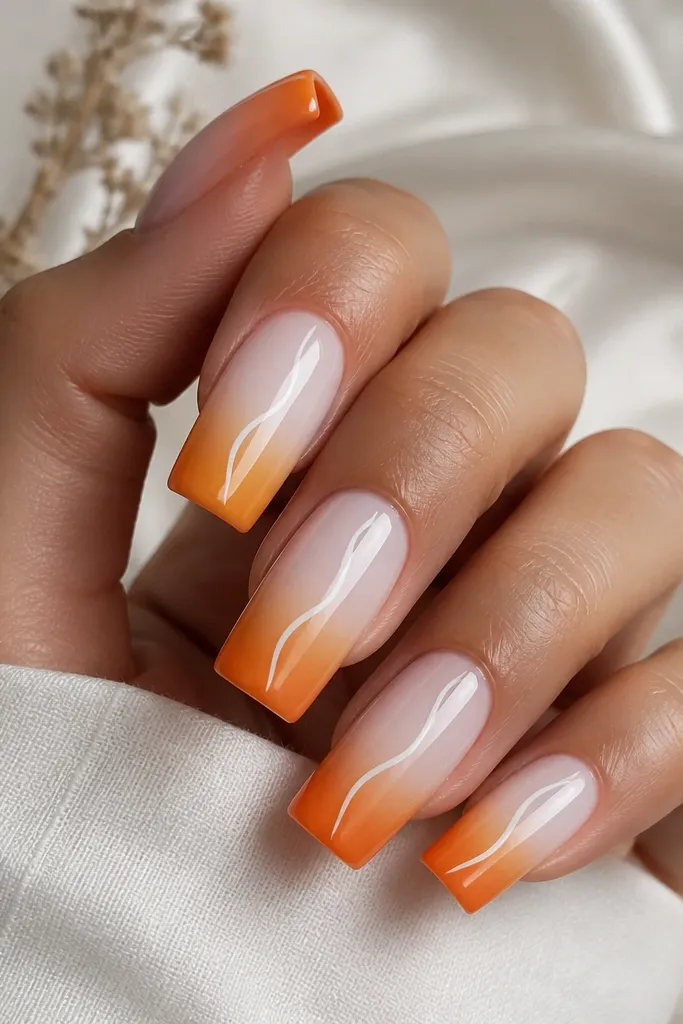 Long square nails with a smooth ombre from milky white near the cuticle to tangerine at the free edge. In the center of each nail, there's a thin white swirl line that curves upward like a ribbon. The finish is glossy, with no glitter.