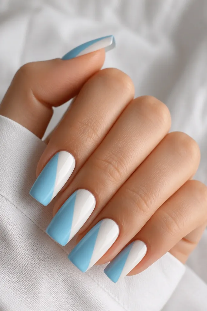 Long square nails with a clean white base. Each nail has a diagonal half-panel of sky blue running from one side of the nail near the cuticle to the opposite corner at the tip. The diagonal edge is sharp and straight. Glossy finish.