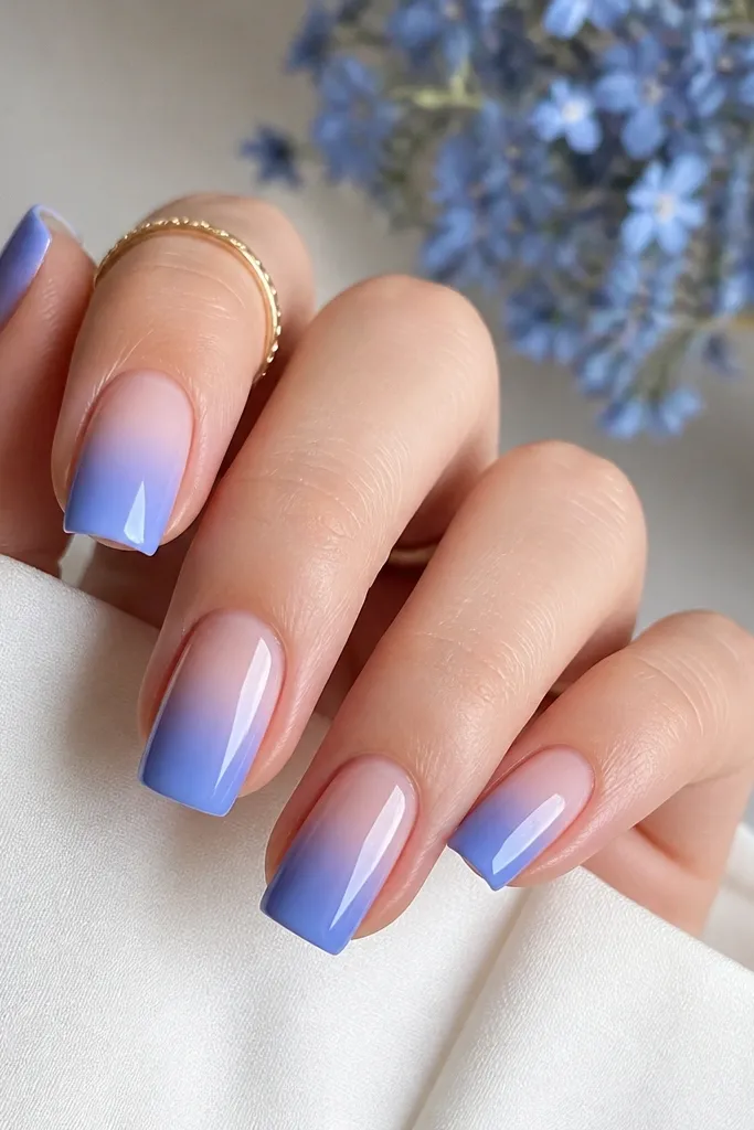Square nails with a soft gradient: cornflower blue fades into nude near the cuticle, all glossy and smooth with no harsh banding.