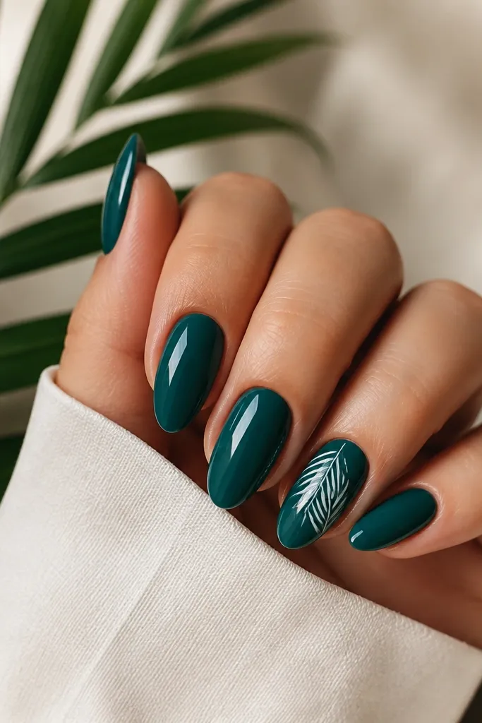Teal glossy almond nails with a single accent nail featuring a small white palm leaf near the cuticle. The leaf has thin lines and a clean stem.
