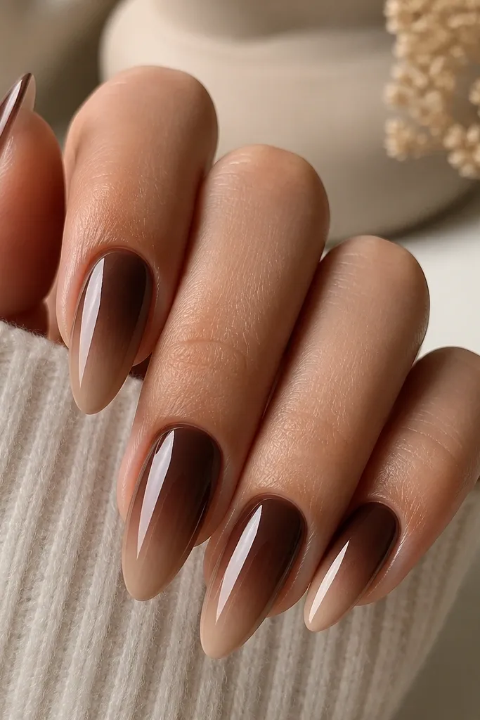 Almond nails with a chocolate brown base that fades into a nude-beige tip. The ombré is smooth and glossy.