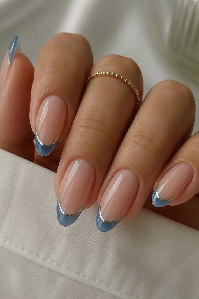 Medium almond nails with a sheer nude base. The French tips are glazed blue (a glossy jelly look), and there's a thin chrome line outlining the tip edge, mirror-like. The overall look is shiny and smooth.