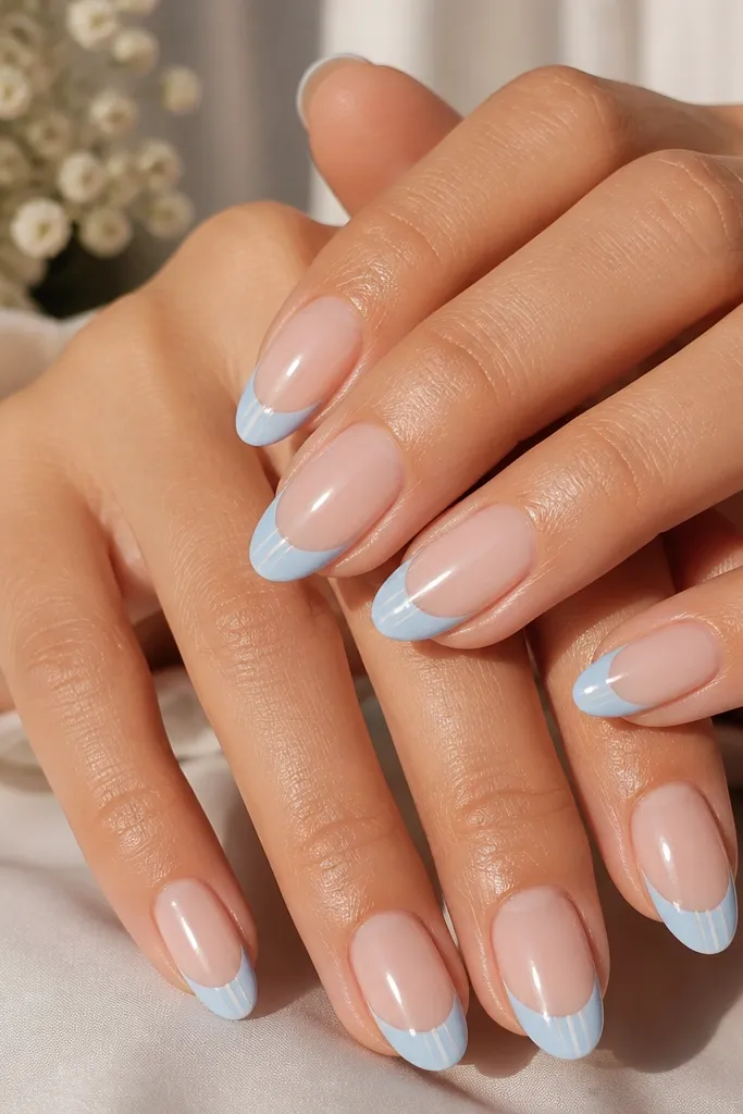 Medium almond nails with a sheer nude base. The French tips are baby blue and glossy. On each tip, there are two tiny white vertical stripes - one near the left sidewall and one near the right sidewall. Clean, symmetrical placement.
