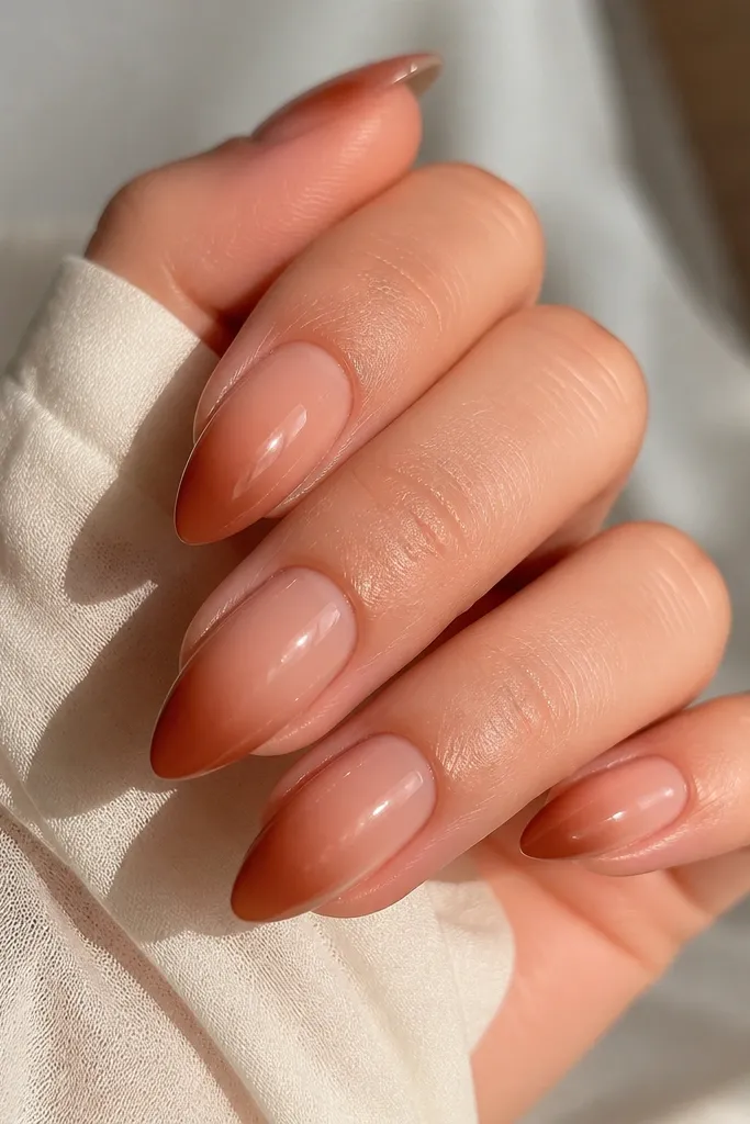 Almond nails with a warm pink nude base. The tips fade into a cinnamon brown ombré, soft and smoky, with a glossy top coat.