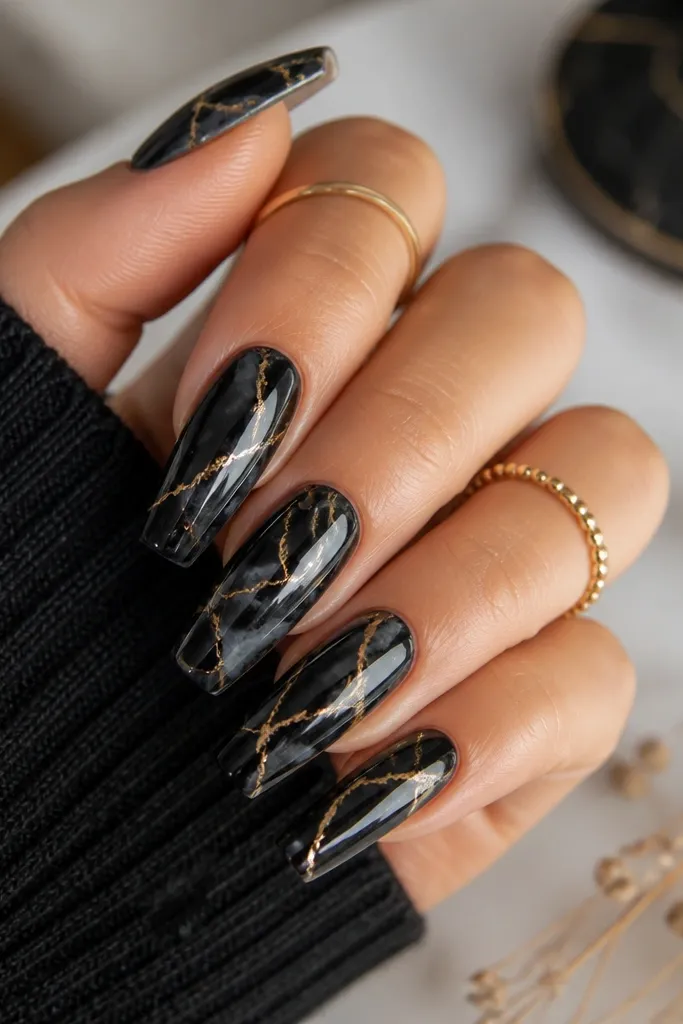 Medium coffin nails with a black marble base in smoky swirls. Honey-gold veins run through the marble like thin cracks, and the top coat is glossy and reflective.