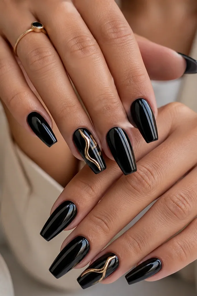 Medium coffin nails with a black base and a French side detail in black. One or two accent nails have a flowing gold swirl across the center, glossy and raised.