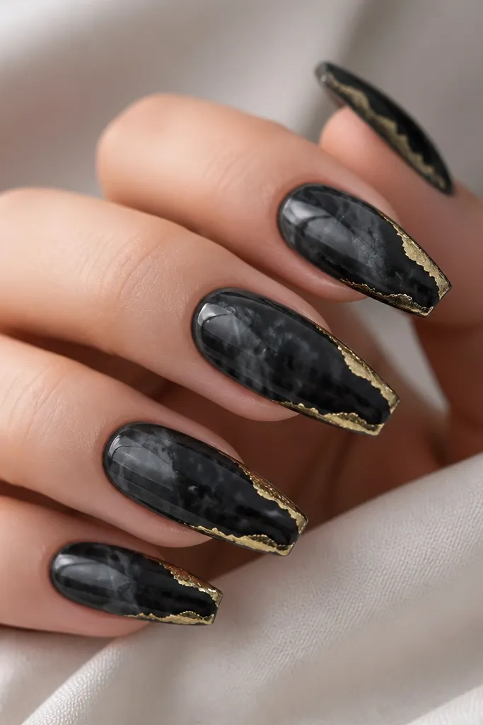 Medium coffin nails with glossy black marble swirls. A thin gold foil strip frames the outer edges along one side and near the tips, creating an irregular border.