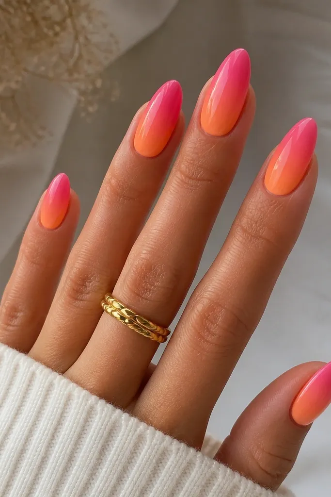 Almond nails with a smooth creamsicle orange fade at the base transitioning into bright hot pink at the tips, glossy finish with no harsh lines.