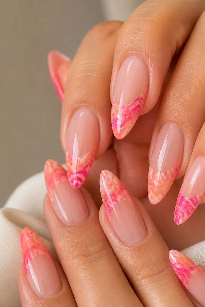 Long almond nails with nude base and marble effect only on the tips in hot pink and orange, glossy finish.