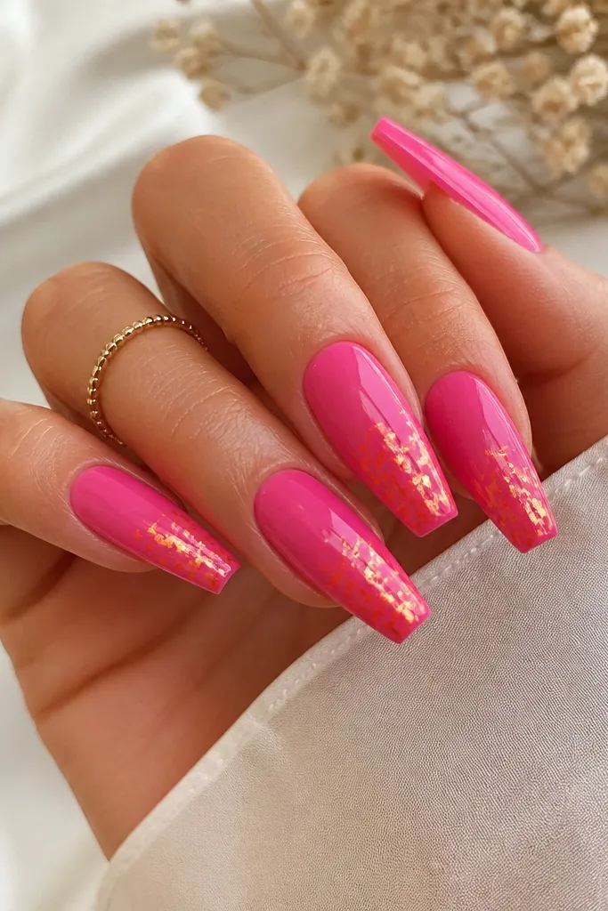 Medium coffin nails in glossy hot pink with scattered orange foil flakes on the lower half, high-shine finish.