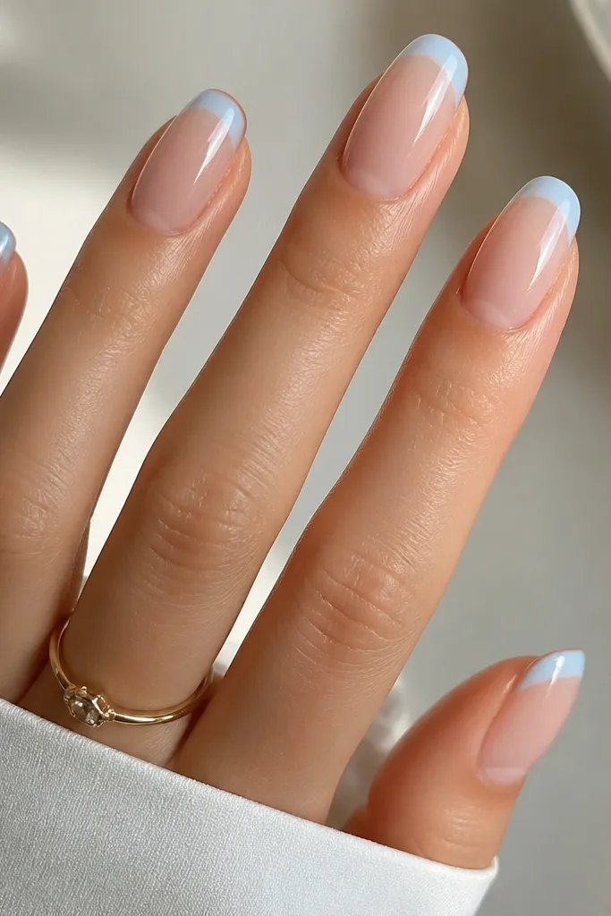 Medium oval nails with a nude jelly base that looks hydrated and slightly translucent. The French tips are icy sky blue, slightly thicker at the center, glossy and smooth.