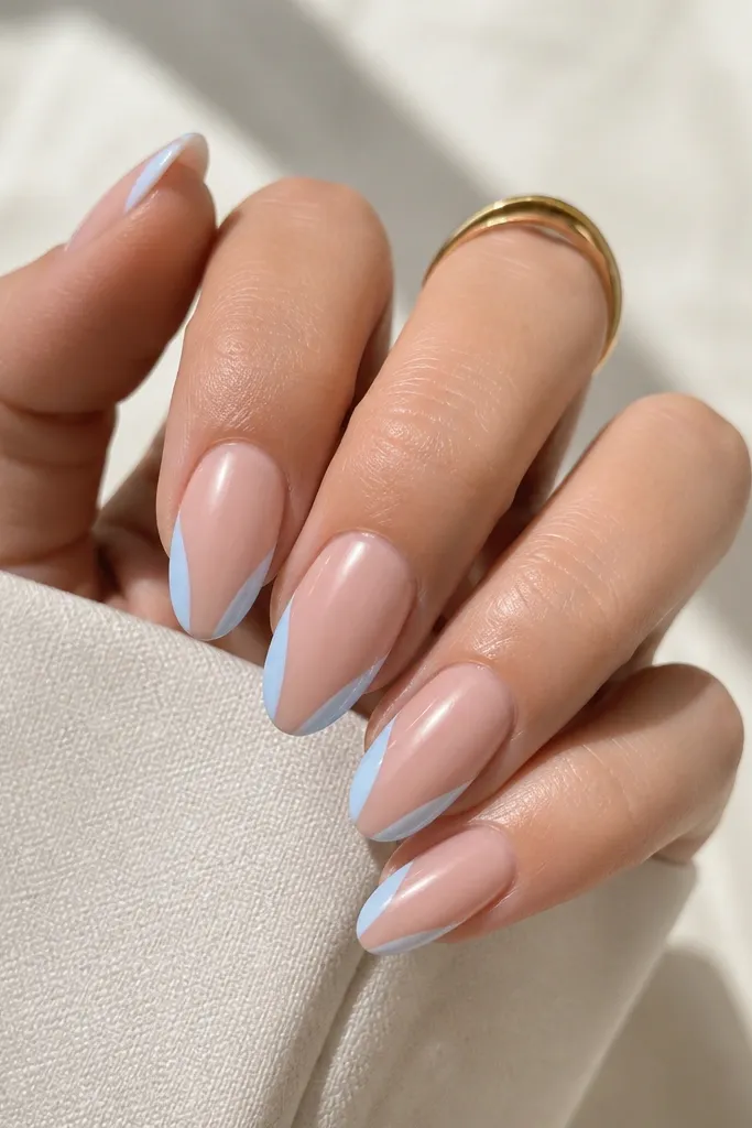 Almond nails with a nude base. The sides of the French tip are painted light blue, while the center of the tip stays clear/nude, creating a negative space stripe down the middle.