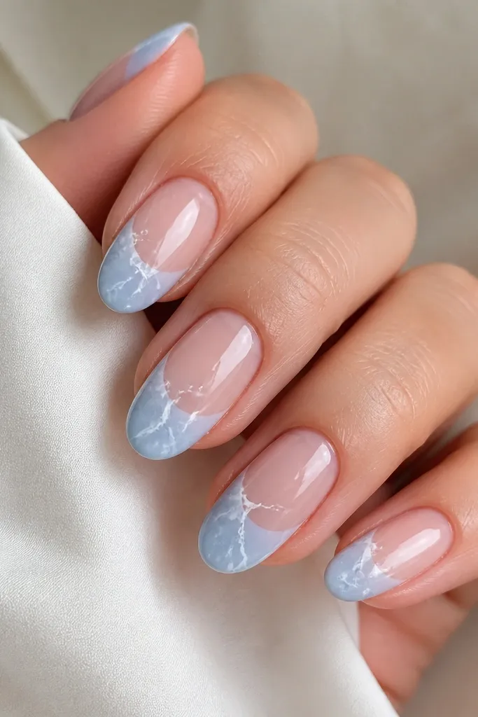 Medium oval nails. Tips are icy light blue with thin porcelain white marble lines running diagonally, like cracks in marble, glossy.
