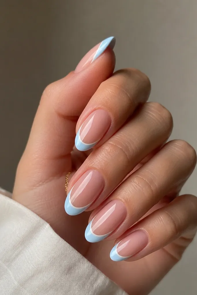 Medium almond nails. The French tip is light blue. Right on the top edge of the French tip, there's a thin white line following the smile curve, glossy.