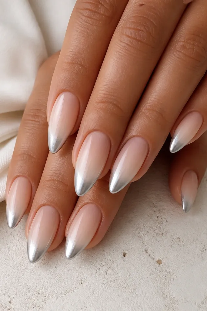 Almond nails with a nude base. The French area looks like a smooth gel fade from nude into white near the smile line, then the outer tip is silver chrome.