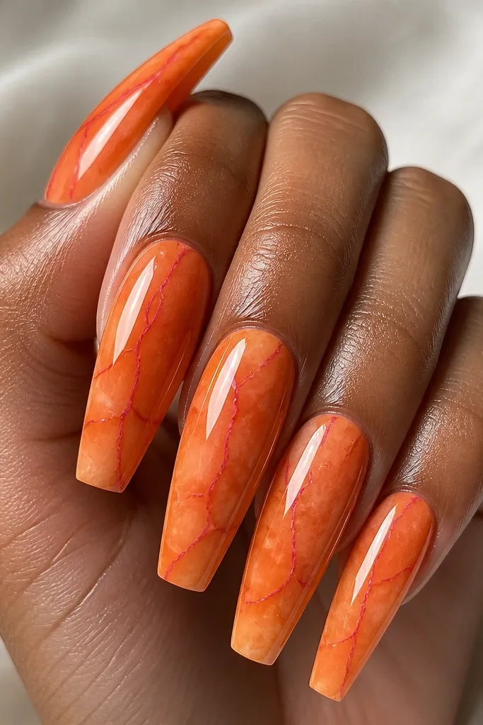 Coffin nails with orange marble base and thin pink vein lines. The veins are straight-ish and slightly curved, like cracks. Glossy top coat makes the pattern pop.