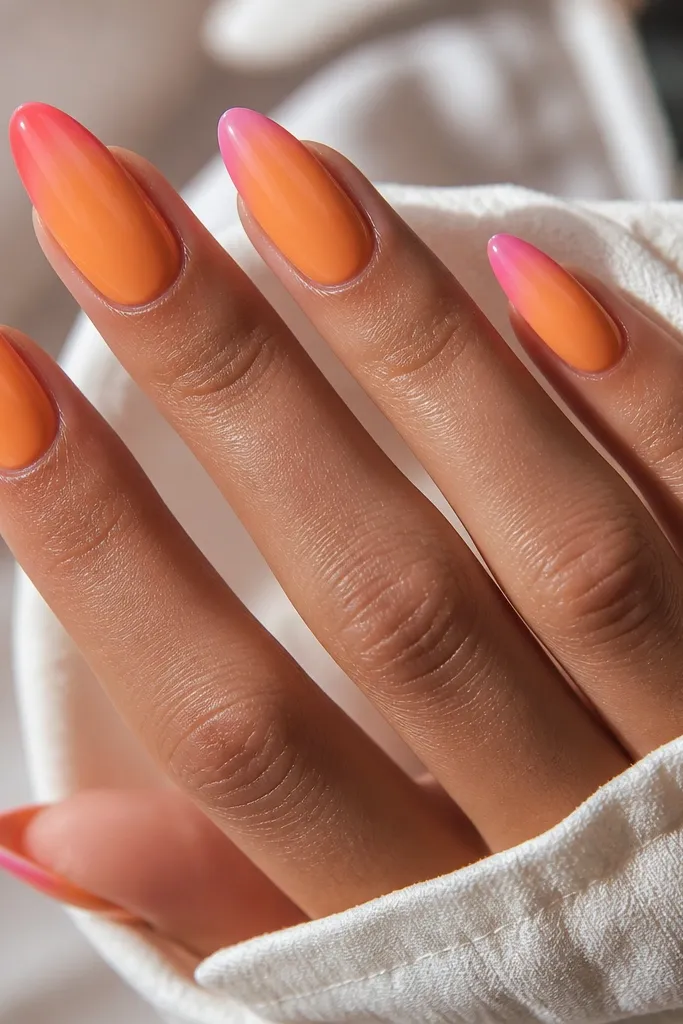 Long almond nails. Orange base with a pink tip that looks like a waterfall - it's thicker at the center and breaks into curved edges on both sides. Smooth gradient at the edge, glossy.