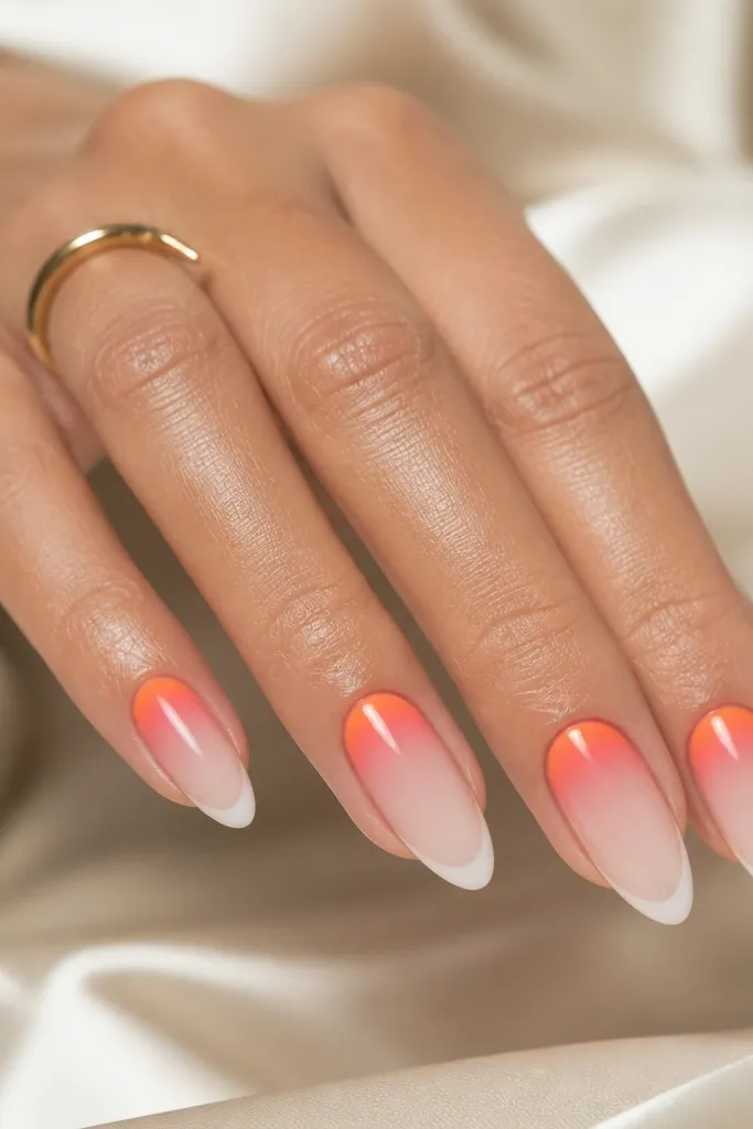 Almond nails with a reverse French look: the cuticle area is orange fading into pink, and the tip has a crisp sheer line. The rest of the nail is sheer, and the gradient is glossy.