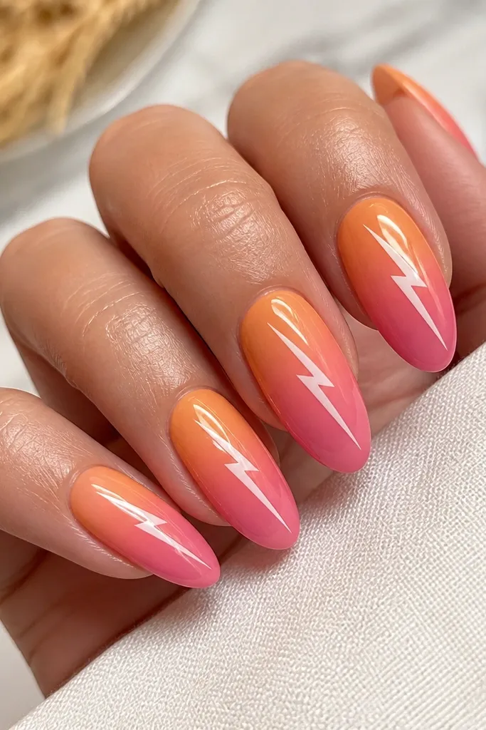Almond nails with orange-to-pink ombre. A thin white lightning bolt runs diagonally across the middle of each nail, crisp and centered. Glossy top coat over everything.