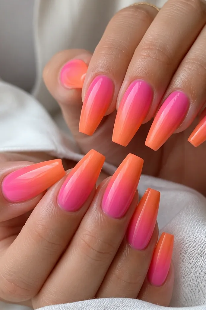 Coffin nails with a gradient that looks centered: pink is strongest in the middle, while orange is stronger on the sides and fades toward the tip. Glossy finish with smooth blending.