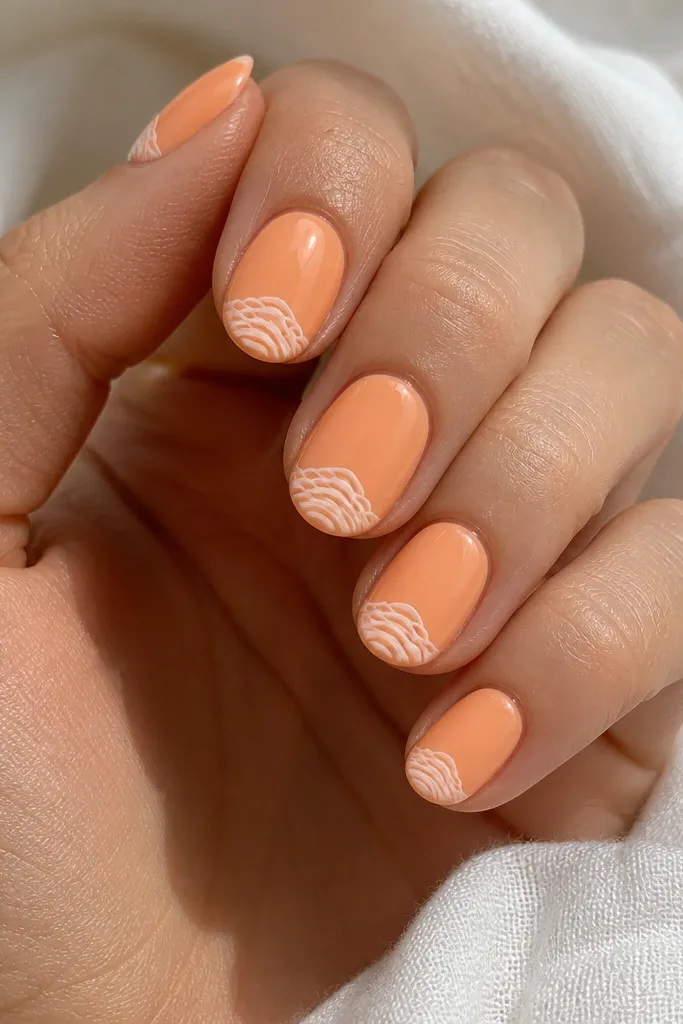 Short oval nails painted creamsicle orange. The tips have thin white curved ridges stacked like a seashell, with a glossy clear topcoat. No gems, just crisp lines.