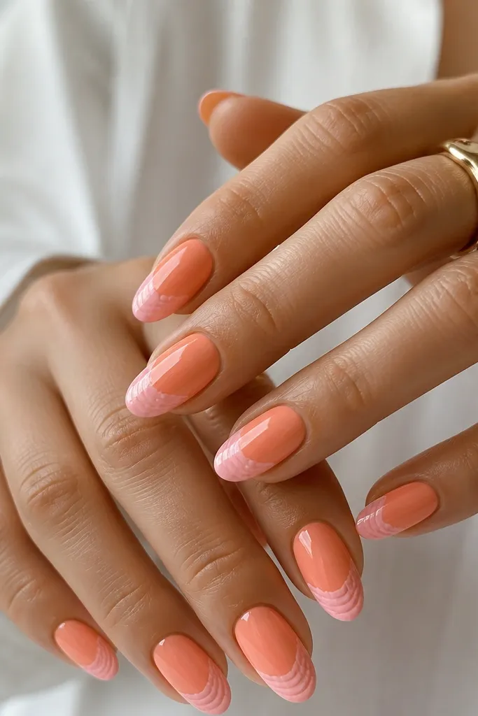 Medium almond nails in peachy orange. Shell ridges near the tip are soft pink, layered in a few curves. Glossy finish, no glitter.