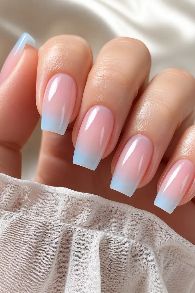 Long square nails with a translucent pink glassy base. The French tips fade from pale water-blue at the edge to almost clear near the smile line, glossy and smooth.