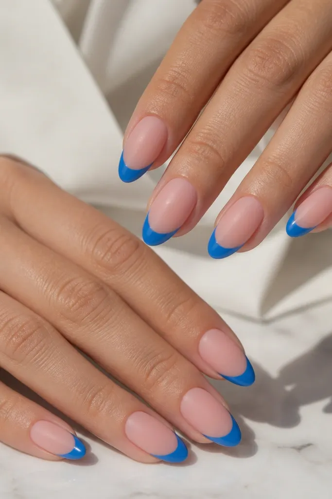 Medium almond nails with matte pink base. The French tips are glossy blue with a sharp smile line, creating a clear matte-gloss contrast.