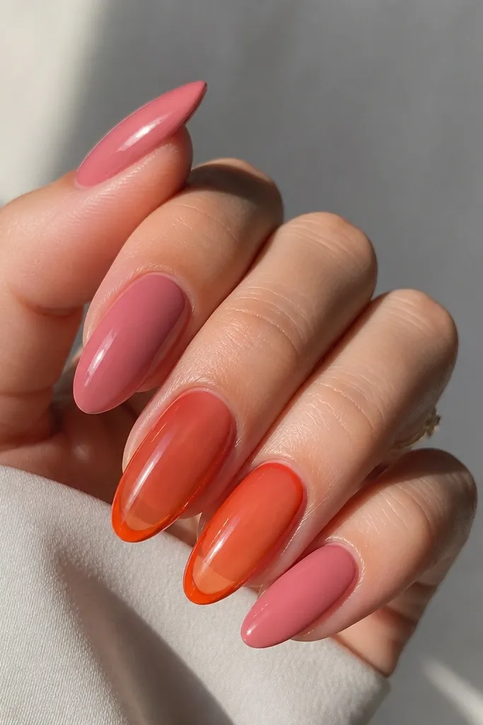 Most nails are glossy pink almond nails, and one or two nails are orange jelly with a translucent center and brighter orange edges; smooth, glassy look.