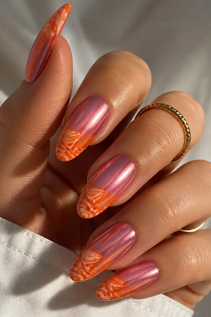 Pink chrome nails with the tips covered in orange marble. The marble has swirling orange, peach, and pale cream lines under a glossy chrome-like finish. The rest of the nail stays mirror pink.
