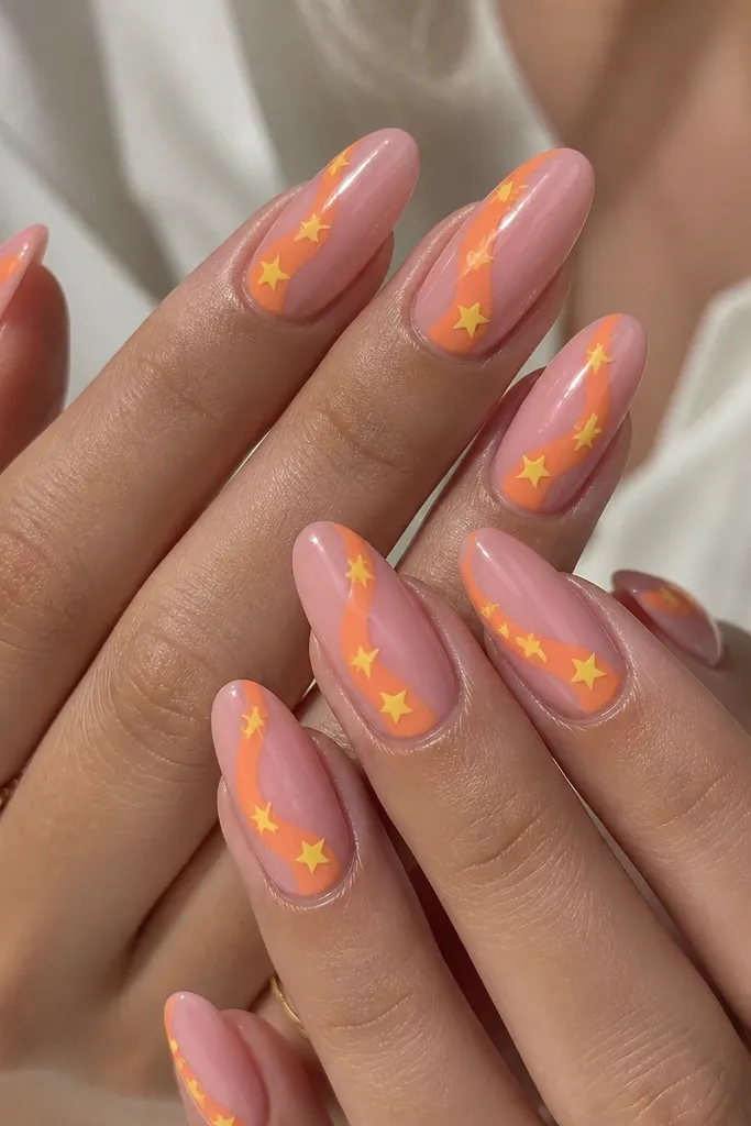 Long almond nails with a glossy pink base. One sweeping orange swirl runs diagonally across each nail, and tiny five-point yellow stars sit near the swirl's edge.
