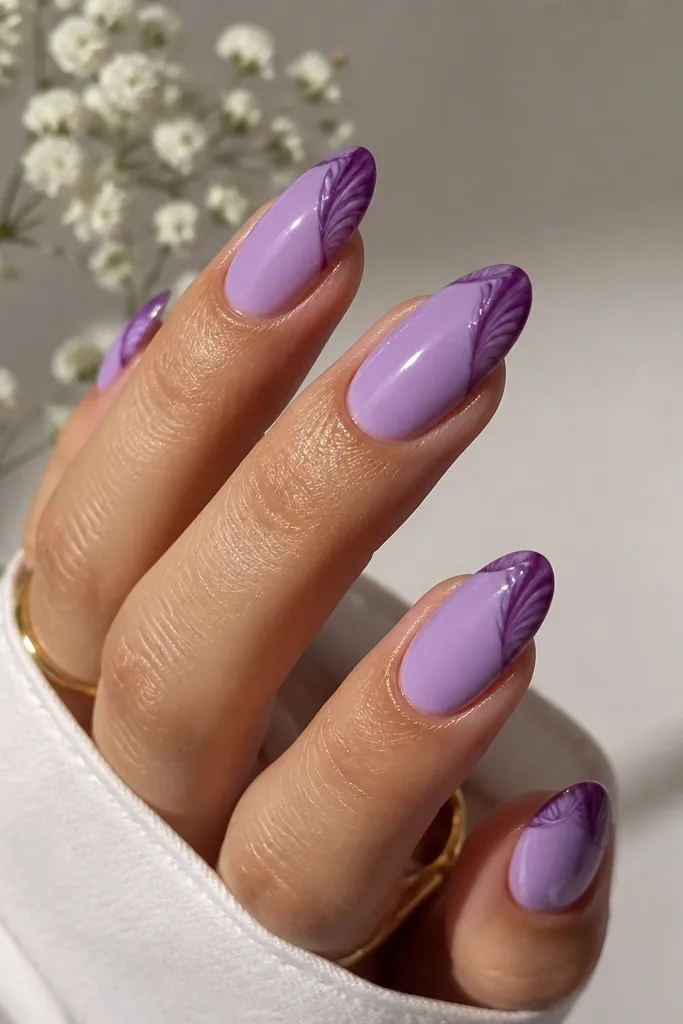 Medium almond nails. Base is soft lavender. Each nail has a deeper grape rim tracing a curved shell edge, with subtle ridge lines inside the rim. The topcoat is glassy and slightly reflective.
