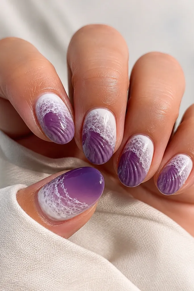 Assorted nails: four nails have purple shell ridges with a milky white foam edge. The thumb nail has a smooth gradient from deep grape to lavender with a white foam wave fading across it. All nails glossy.