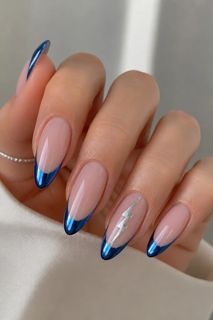 Long almond nails with a classic blue chrome French tip; on the ring finger, a silver foil lightning bolt cuts diagonally through the nude area just under the blue line; ultra shiny chrome with crisp edges.