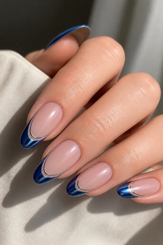 Long oval nails with blue chrome French tips; a thin silver halo line sits just below the blue edge on the nude area; mirror finish with crisp double-line effect.