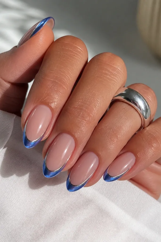 Medium oval nails with blue chrome French tips; two thin metallic silver stripes run down each side near the free edge, creating a pinstripe frame; nude base, mirror shine.