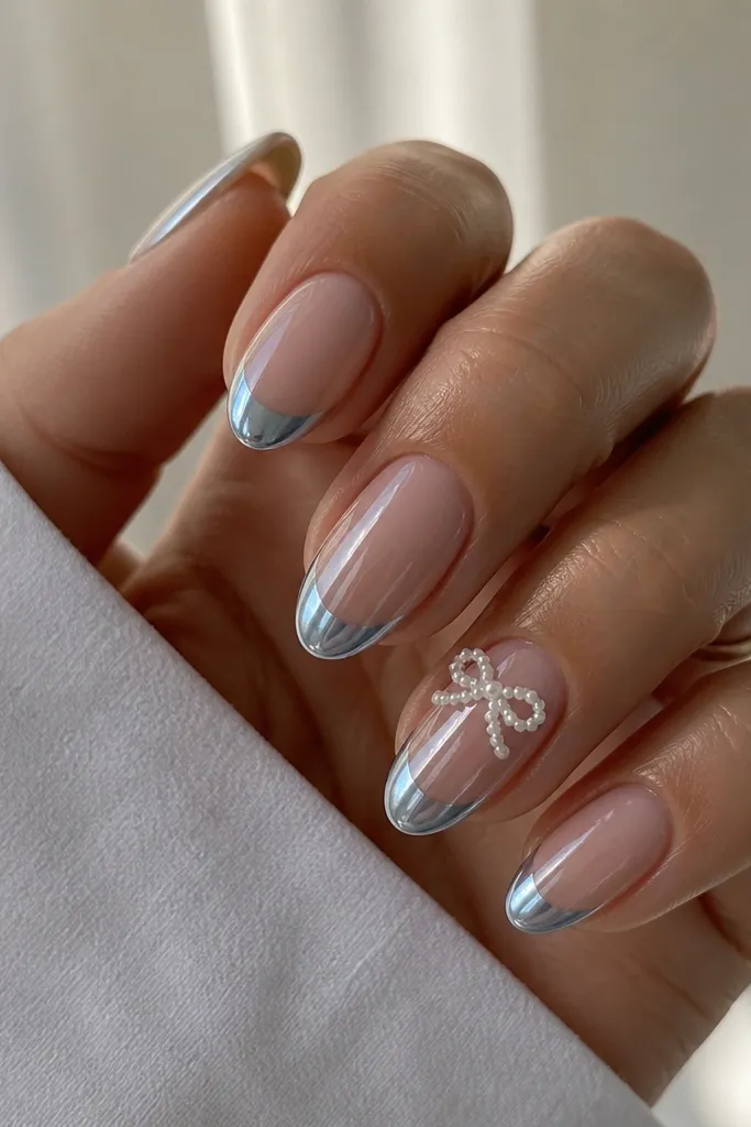 Medium almond nails with icy blue chrome French tips; ring finger has a small white pearl bow placed at the center of the nail just under the blue line; other nails are plain chrome French; glossy mirror finish.