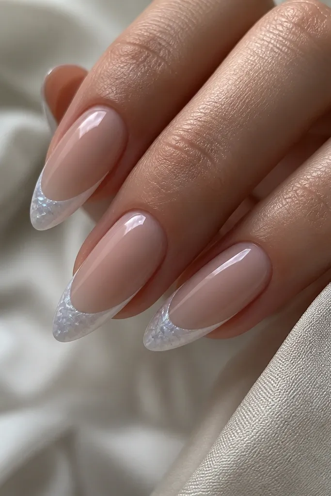 Long almond nails with a sheer nude base. French tips are icy white, slightly translucent. The shell texture inside the tip looks like tiny blue-tinted ridges and micro dots, like frost on shell.