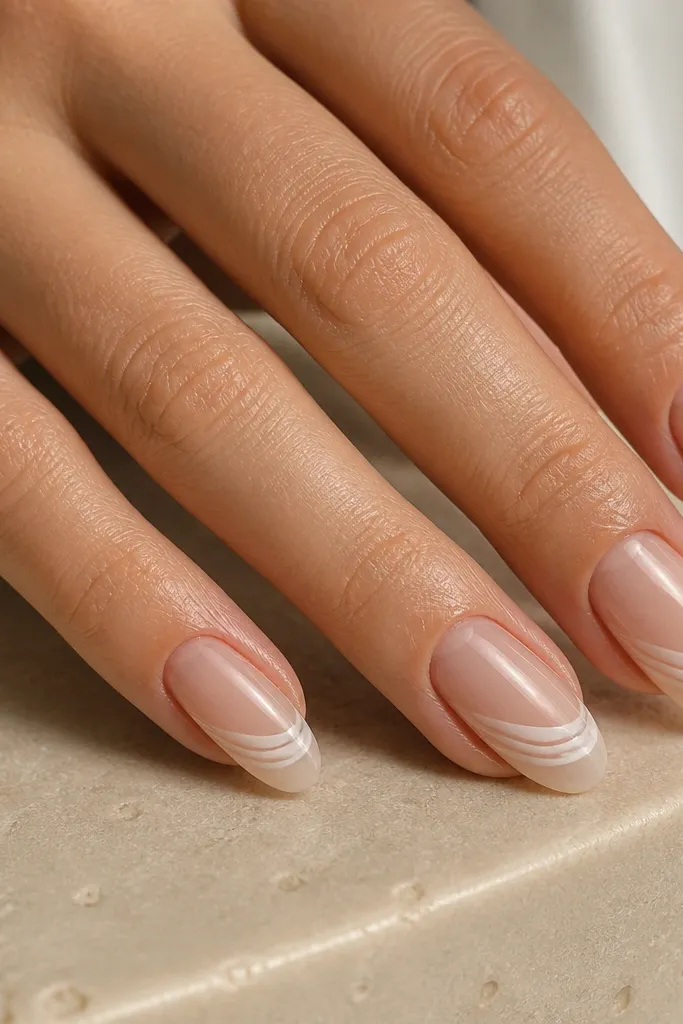 Nails have a sheer nude base with a soft white French fade at the tips. On the fade area, there are 2-3 tiny milky white micro lines that curve like shell ribs.